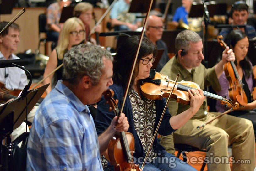 The violins practice before recording a cue